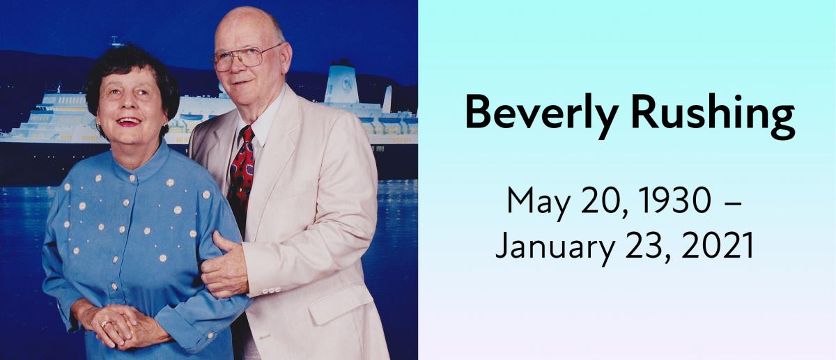 Beverly Rushing standing next to her husband, smiling, in front of a boat. May 20, 1930 — January 23, 2021.