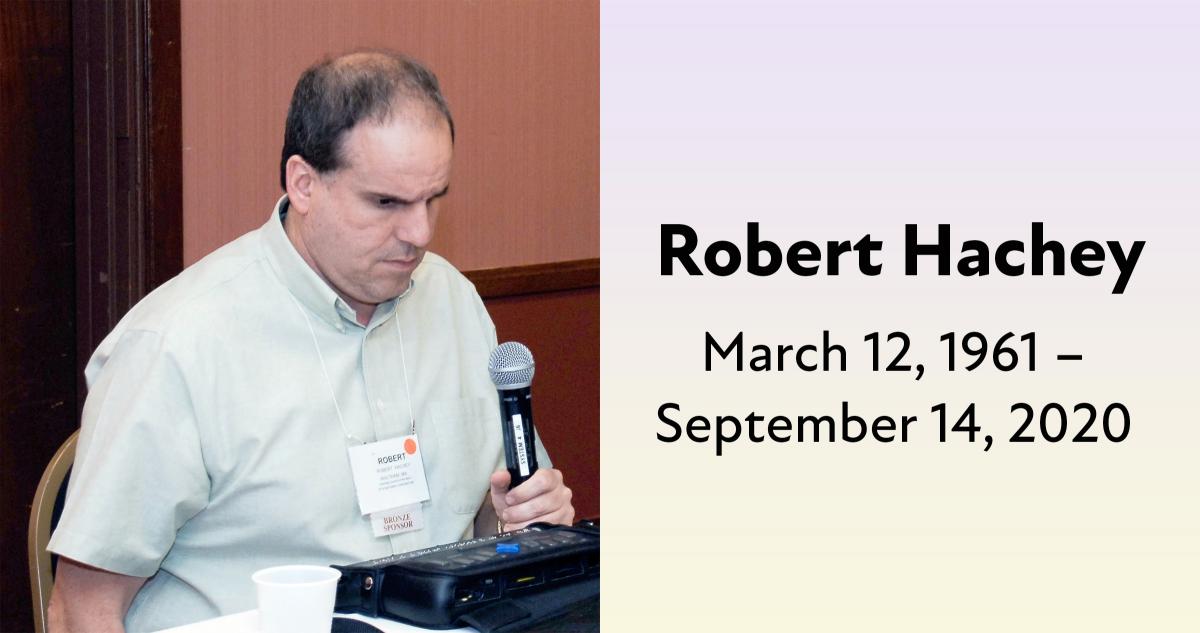 Bob sits with a microphone in his hand and a braille display in front of him. Robert Hachey March 12, 1961 –  September 14, 2020.