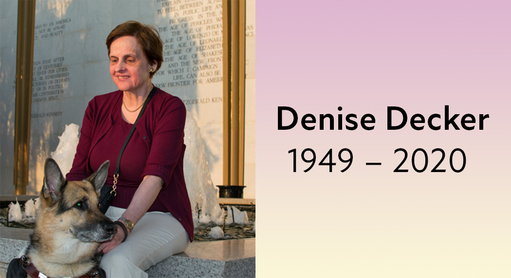 The sun shines on Denise's face as she smiles and sits by a water fountain at a monument with her german shepherd guide dog. Denise Decker, 1949 − 2020.