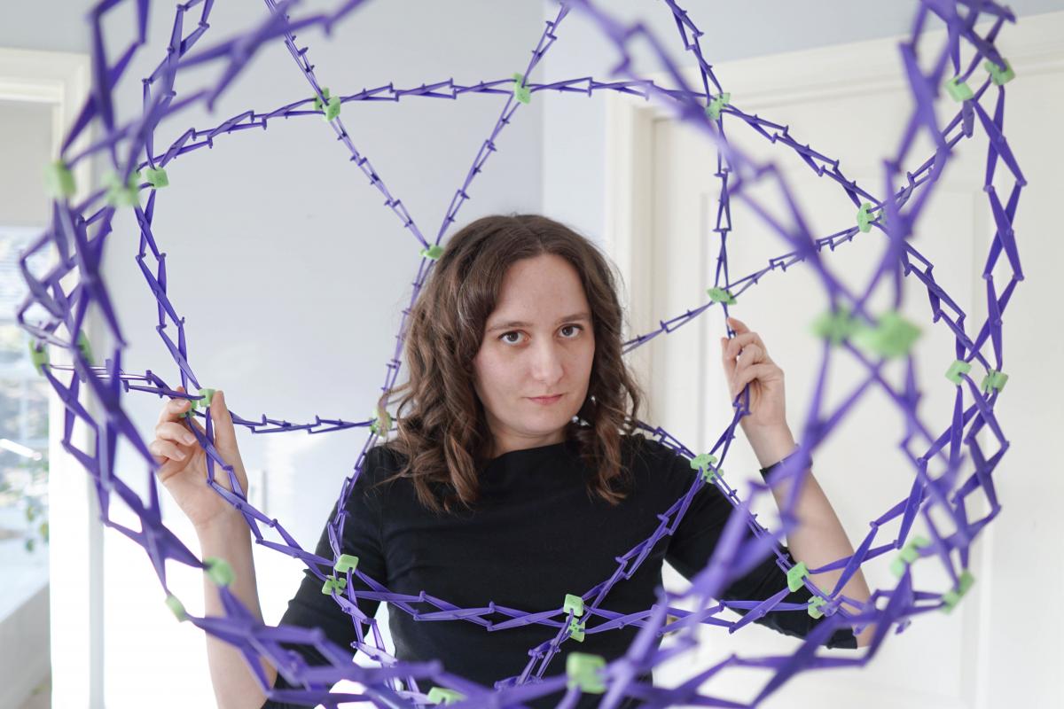 Kelly Lepo, standing inside a purple Hoberman sphere, an expanding sphere toy.
