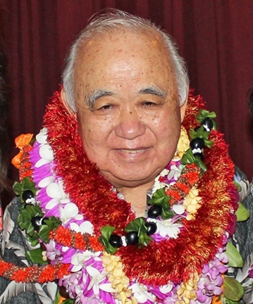 Warren smiles as he wears multiple lei garlands.