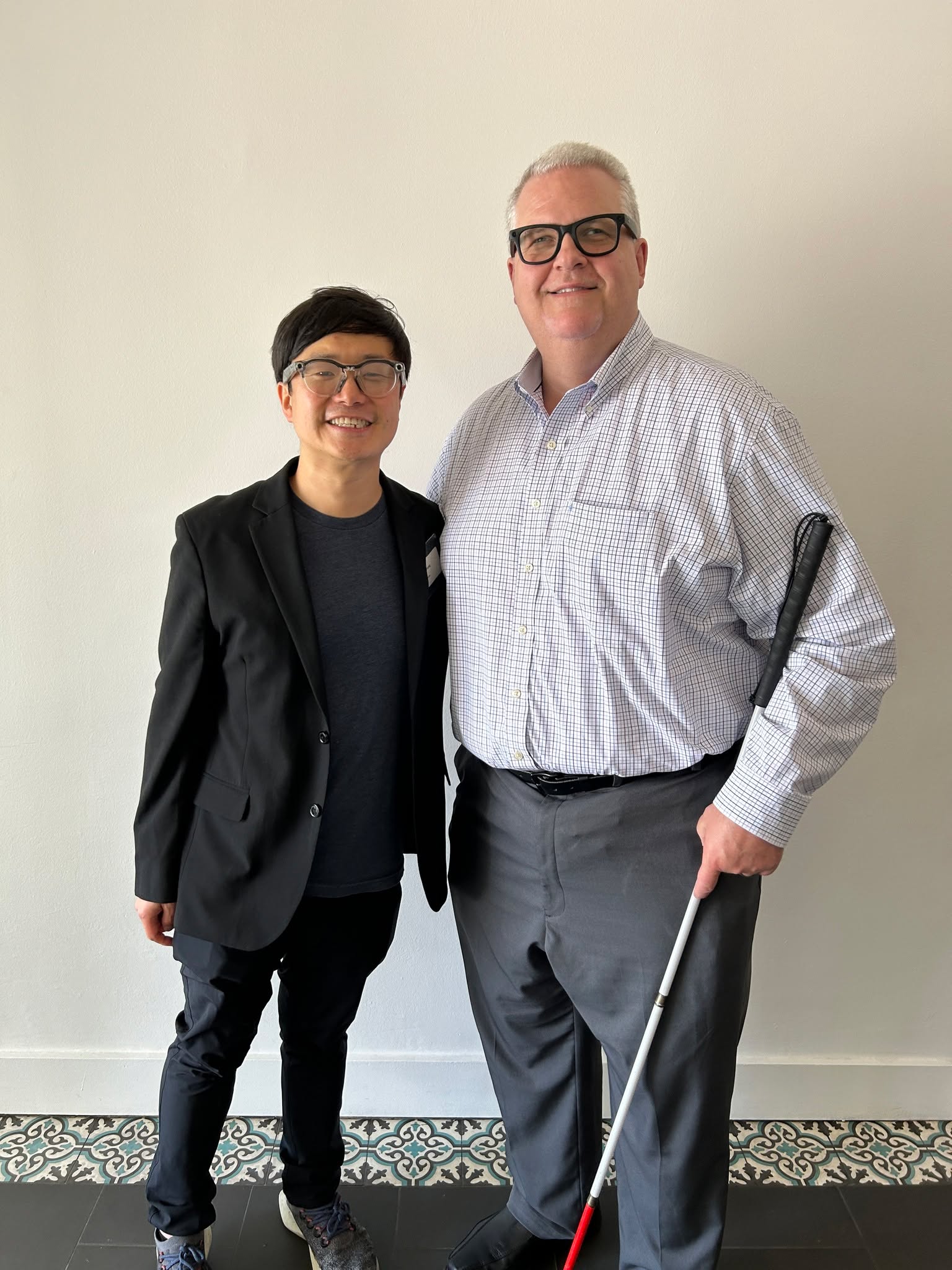 Pictured are Executive Director Scott Thornhill (right) standing with Meta’s Accessibility Innovation Lead, Fan Zhang (left). Both are wearing Ray-Ban Meta AI glasses.