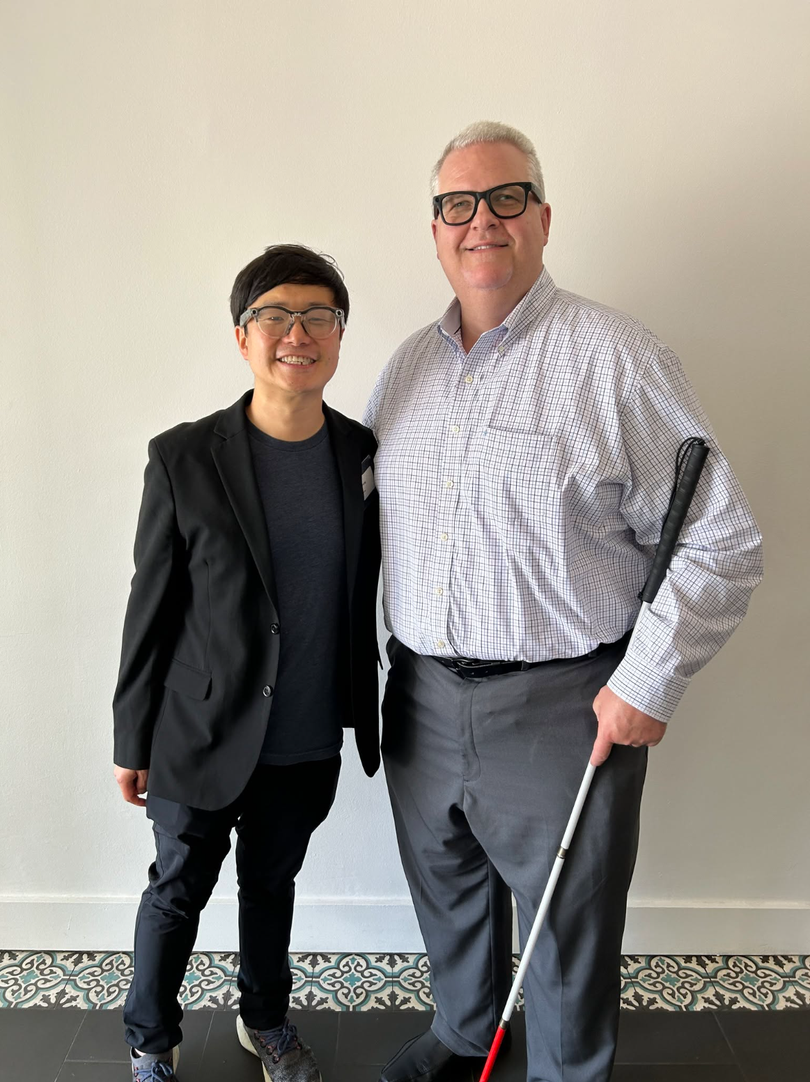 Pictured are Executive Director Scott Thornhill (right) standing with Meta’s Accessibility Innovation Lead, Fan Zhang (left). Both are wearing Ray-Ban Meta AI glasses.